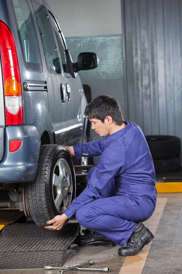 Meccanico che cambia la gomma dell'auto fotografia stock