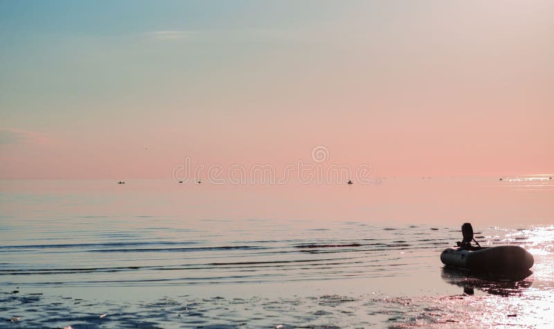 Gommone con un motore nel mare contro un tramonto rosa immagini stock libere da diritti Gommone con un motore nel mare contro un tramonto rosa immagini stock libere da diritti