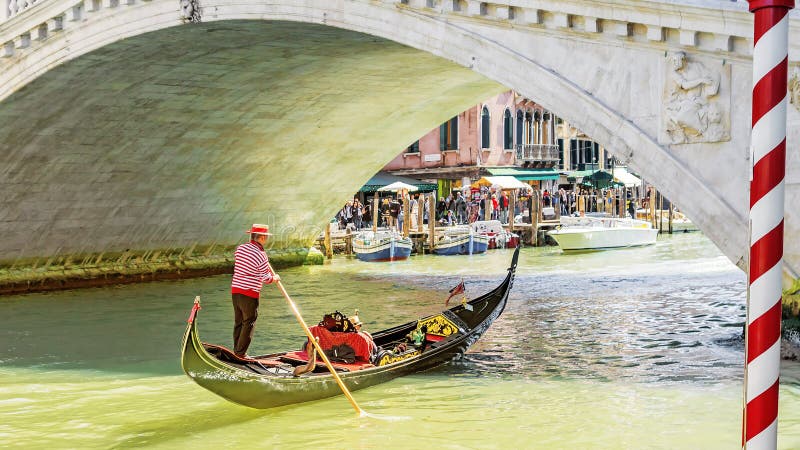 Gondolier under the Rialto Bridge of Venice, Italy