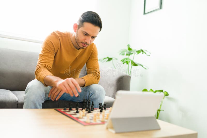 Young pensive man sitting and playing chess online