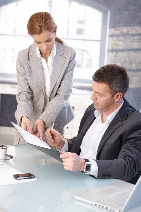 Good-looking boss signing contract at desk stock images Good-looking boss signing contract at desk stock images