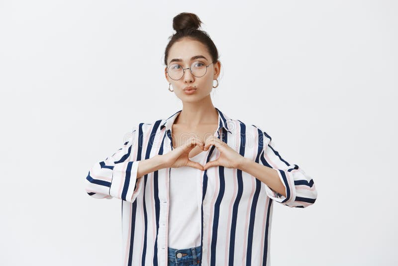 Good-looking feminine fashion blogger shaping heart with hands over chest, folding lips in kiss, giving mwah, taking stock photos Good-looking feminine fashion blogger shaping heart with hands over chest, folding lips in kiss, giving mwah, taking stock photos
