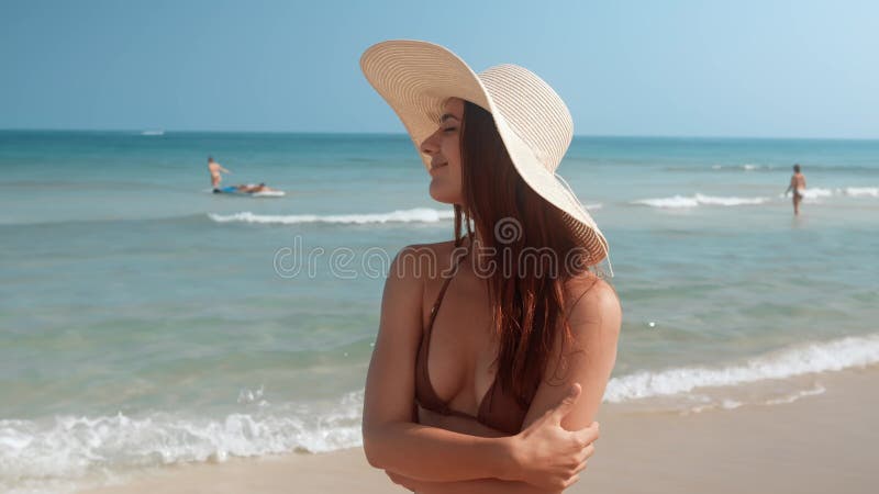 Good looking slim woman stands on beach posing on camera. Beach vacation ambiance woman showcases slim beautiful body