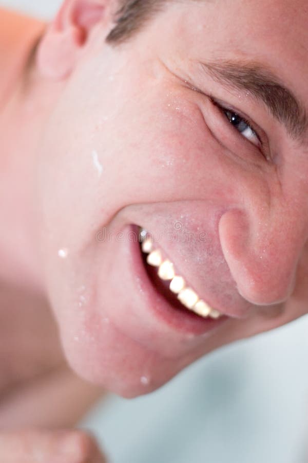 Man with blue eyes, cleaning his face and smiling. Man with blue eyes, cleaning his face and smiling