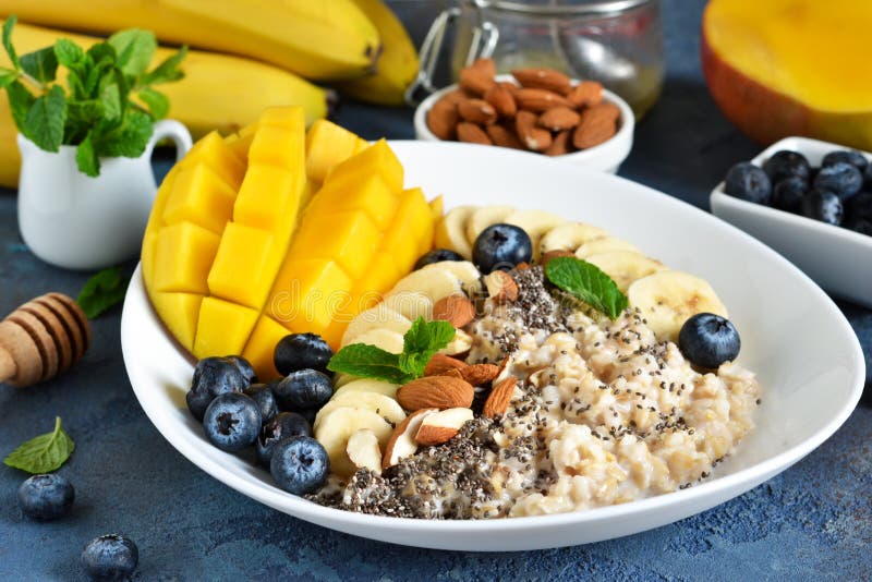 Good morning! Breakfast with oatmeal, banana, mango, blueberries and chia seeds on a concrete background stock photos Good morning! Breakfast with oatmeal, banana, mango, blueberries and chia seeds on a concrete background stock photos