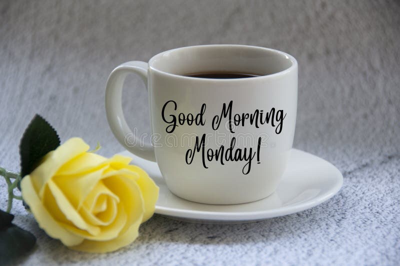 Good morning Monday text on coffee cup yellow flower on blurred marble background. Morning wishes