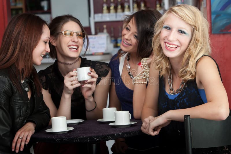 A cute blonde girl smiles while sitting with three friends in a cafe. A cute blonde girl smiles while sitting with three friends in a cafe