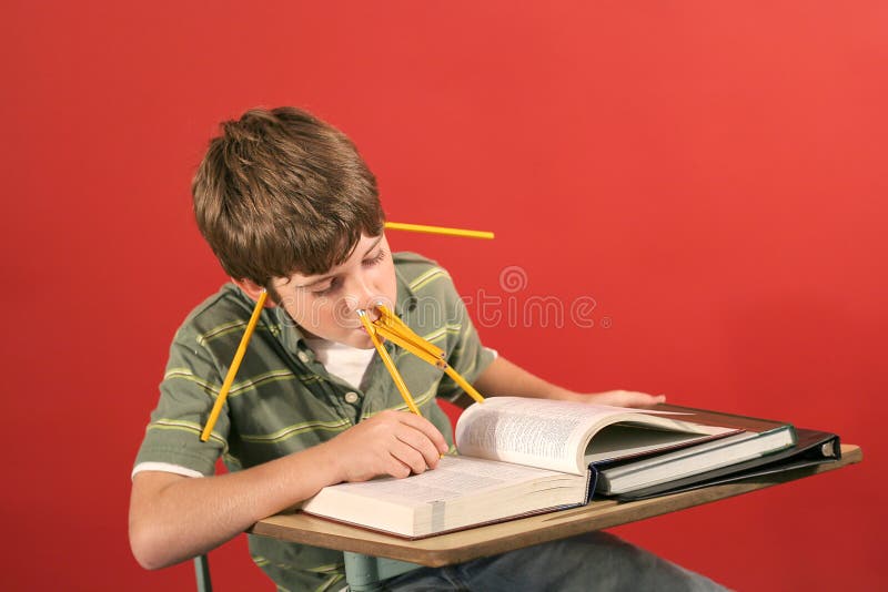 Goofy kid studying with pencil