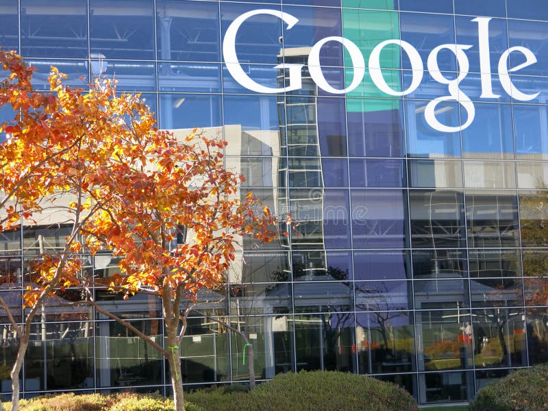 Front of main entrance to Google corporate headquarters filled with glass windows.