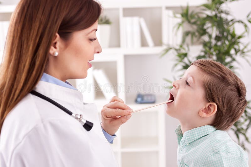 Gorge de examen de sourire de jeune docteur au patient d'enfant photographie stock Gorge de examen de sourire de jeune docteur au patient d'enfant photographie stock