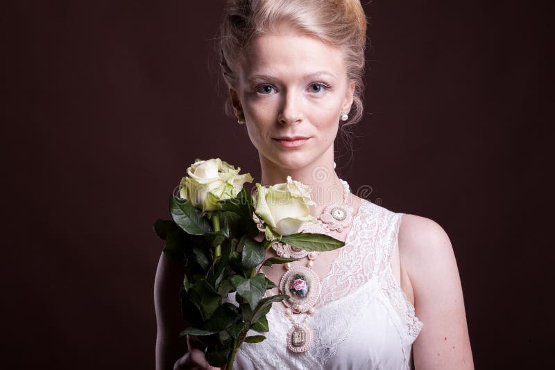 Gorgeous blonde woman in victorian dress with roses in hands