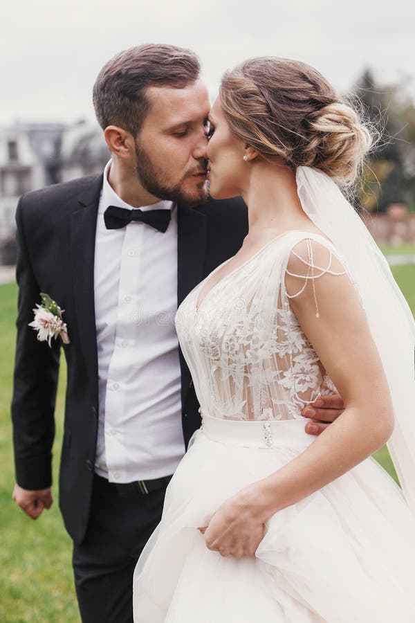 Gorgeous bride and stylish groom gently hugging and kissing outdoors. Sensual wedding couple embracing. Romantic moments of newly royalty free stock photo Gorgeous bride and stylish groom gently hugging and kissing outdoors. Sensual wedding couple embracing. Romantic moments of newly royalty free stock photo