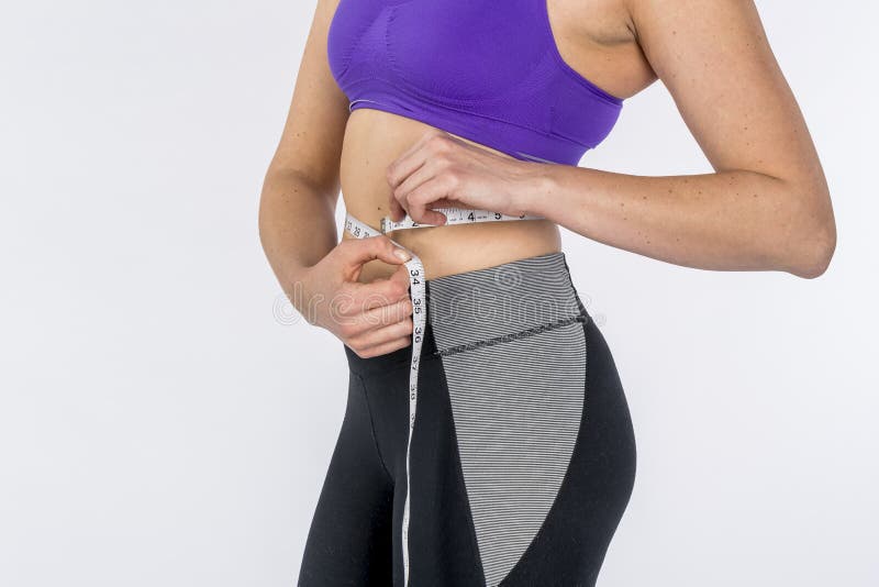 Hot Brunette Fitness Model Measuring Her Waist Against A White Background royalty free stock photo Hot Brunette Fitness Model Measuring Her Waist Against A White Background royalty free stock photo