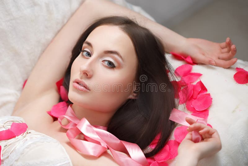 Gorgeous girl lying in rose petals.