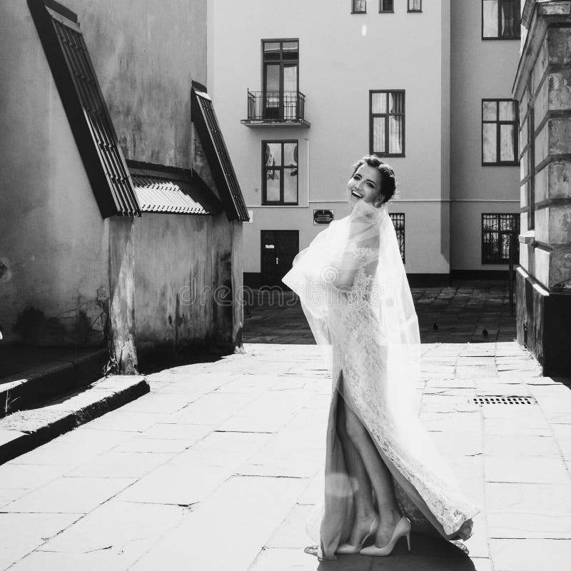 Gorgeous happy smiling brunette bride in vintage white dress posing in the street b&w stock photo Gorgeous happy smiling brunette bride in vintage white dress posing in the street b&w stock photo
