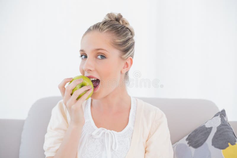 Model Eating Green Apple Sitting on Sofa Stock Photo Image