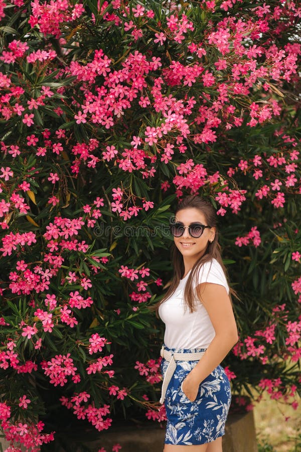 Gorgeous woman in sunglasses stand in beautiful flowers. Portrait of happy smiled young woman royalty free stock images Gorgeous woman in sunglasses stand in beautiful flowers. Portrait of happy smiled young woman royalty free stock images