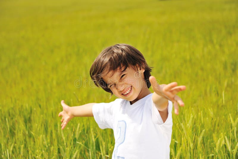Gosse heureux sur la zone verte avec largement image stock Gosse heureux sur la zone verte avec largement image stock