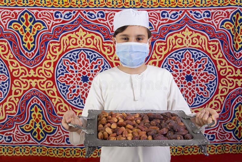 Gosse musulmane présentant un plateau de dattes arabes au ramadan images libres de droits