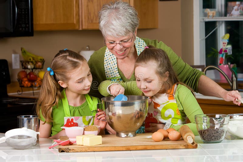 Gosses et traitement au four de grand-maman dans la cuisine image libre de droits Gosses et traitement au four de grand-maman dans la cuisine image libre de droits