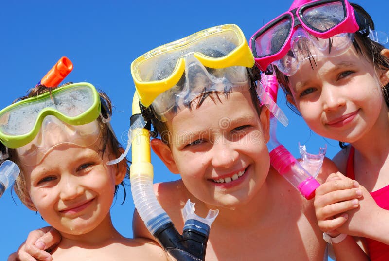 A close up view of three children wearing swimming goggles and snorkels, ready for summer fun in the water. A close up view of three children wearing swimming goggles and snorkels, ready for summer fun in the water.