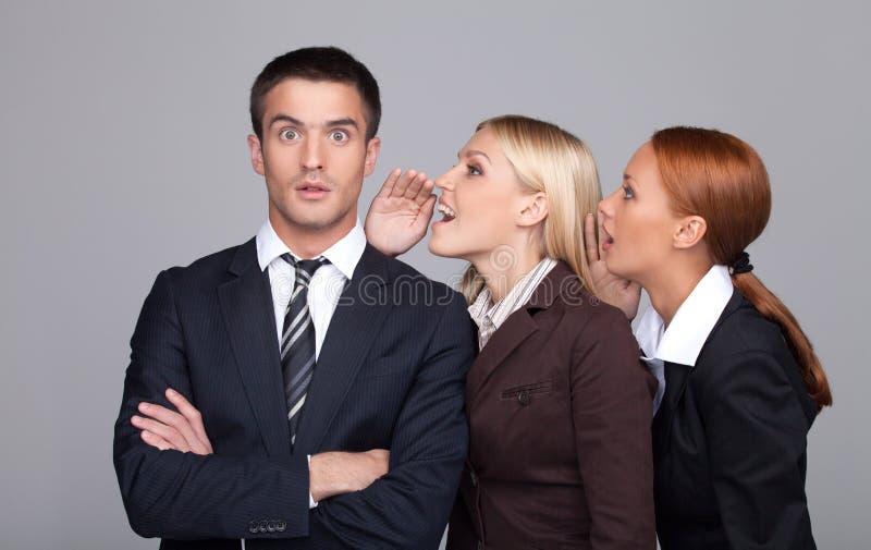 The gossip line. Two beautiful young businesswoman telling gossips to the businessman royalty free stock photo The gossip line. Two beautiful young businesswoman telling gossips to the businessman royalty free stock photo