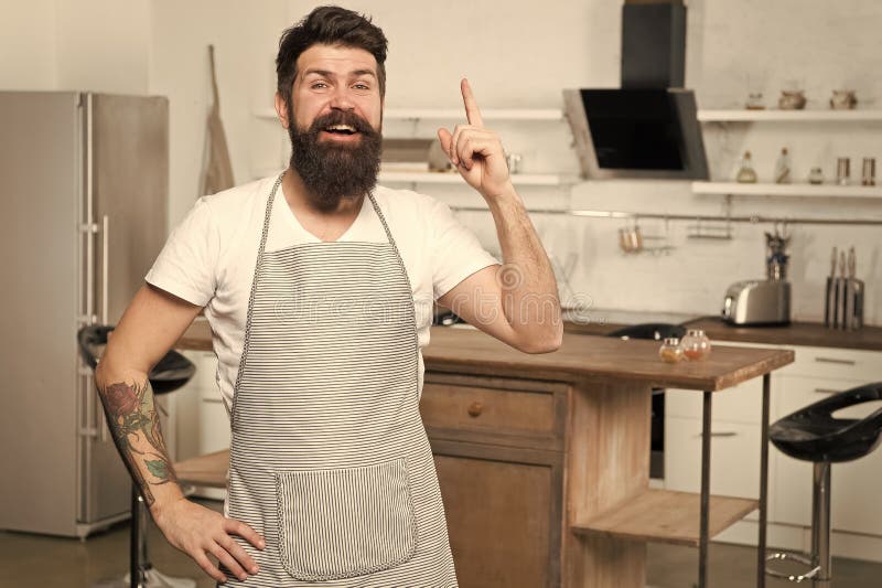Got fresh idea about his recipe. Happy cook keeping finger raised in kitchen. Bearded chef following recipe to impress royalty free stock photo Got fresh idea about his recipe. Happy cook keeping finger raised in kitchen. Bearded chef following recipe to impress royalty free stock photo