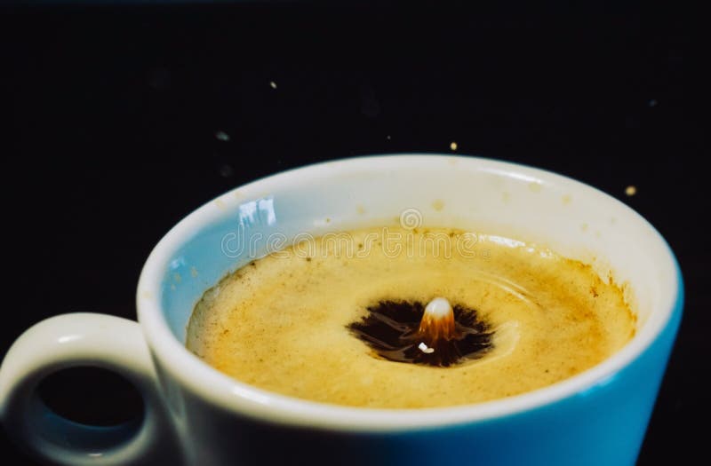 Gota do leite que cai em uma xícara de café imagens de stock royalty free Gota do leite que cai em uma xícara de café imagens de stock royalty free