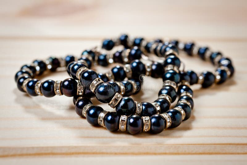 Gotas y una pulsera de perlas negras en un fondo de madera foto de archivo Gotas y una pulsera de perlas negras en un fondo de madera foto de archivo