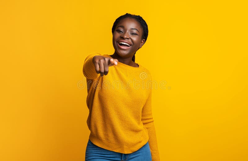 Gotcha. Laughing black lady pointing index finger at camera, indicating somebody, positive african american female having fun while standing over yellow studio background, copy space. Gotcha. Laughing black lady pointing index finger at camera, indicating somebody, positive african american female having fun while standing over yellow studio background, copy space