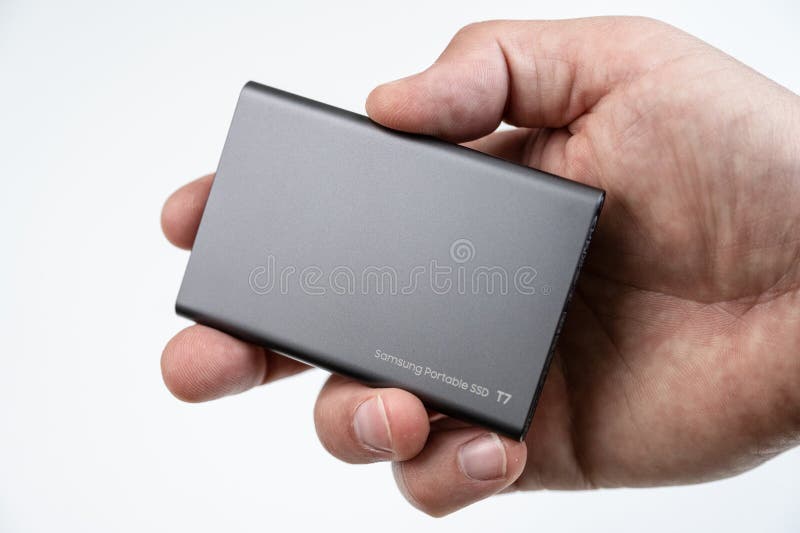 Hand holding a fast Samsung T7 1TB external USB-C SSD hard drive...