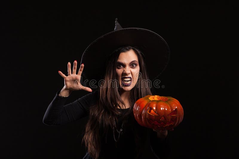 Gotische jonge vrouw in het kostuum die van heksenhalloween zich over zwarte achtergrond bevinden stock foto Gotische jonge vrouw in het kostuum die van heksenhalloween zich over zwarte achtergrond bevinden stock foto