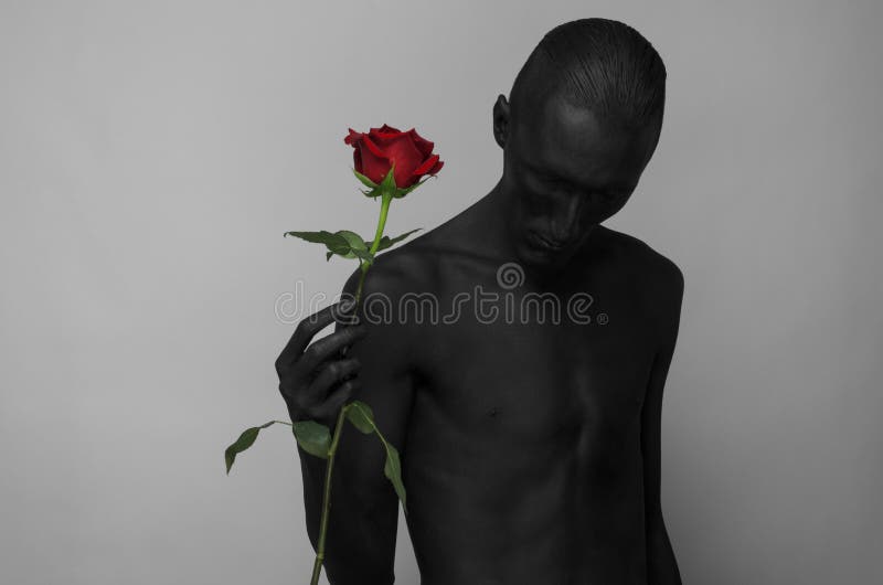 Gotisches und Halloween-Thema: ein Mann mit der schwarzen Haut, die eine rote Rose, schwarzen Tod auf einem grauen Hintergrund im lizenzfreies stockfoto Gotisches und Halloween-Thema: ein Mann mit der schwarzen Haut, die eine rote Rose, schwarzen Tod auf einem grauen Hintergrund im lizenzfreies stockfoto