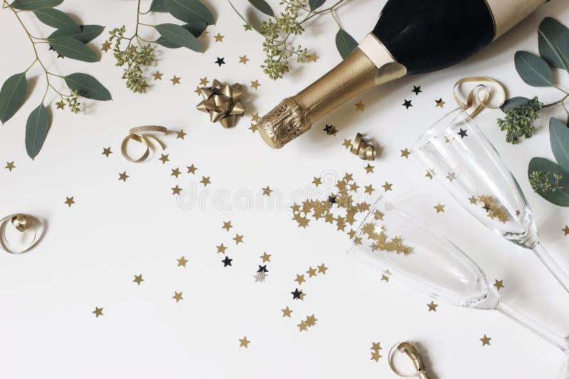 Gott nytt års sammansättning Champagnglas och vinflaska med gyllene konfektstjärnor och eucalyptus-förgreningar arkivbilder