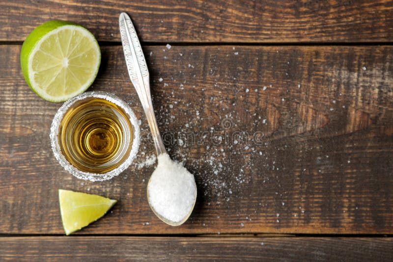Gouden tequila in een glas met zout en kalk op een bruine houten lijst Alcoholische dranken Hoogste mening royalty-vrije stock afbeeldingen Gouden tequila in een glas met zout en kalk op een bruine houten lijst Alcoholische dranken Hoogste mening royalty-vrije stock afbeeldingen