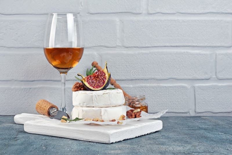 Gourmet appetizer of white brie cheese or camembert with fresh figs, nuts and glass of wine for tasting