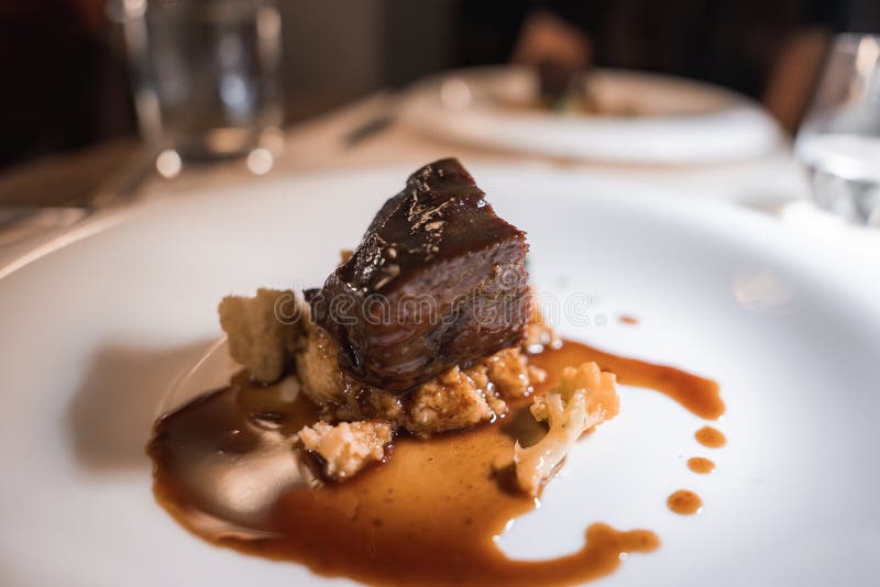 Gourmet Brazed Meat Dish with Artistic Presentation in Fine Dining Setting royaltyfri foto