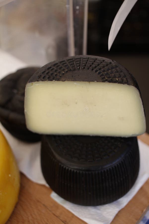 Gourmet cheese. Yellow goat cheese and cheese in a sepia ink wrap. Delicatessen cheeses. Delicious cheese. Farm made organic. stock photo Gourmet cheese. Yellow goat cheese and cheese in a sepia ink wrap. Delicatessen cheeses. Delicious cheese. Farm made organic. stock photo