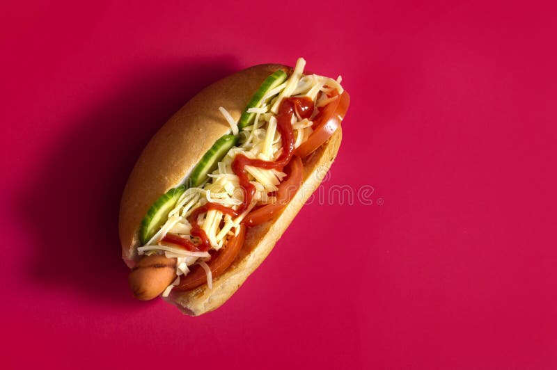 Gourmet dirty hot dog sandwich with various garnish on black slate