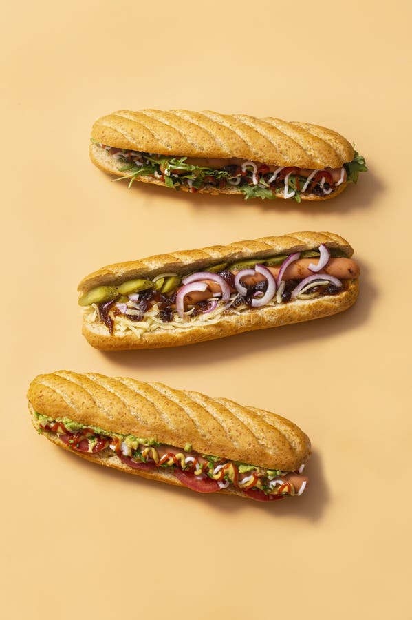 Gourmet dirty hot dog sandwich with various garnish on black slate