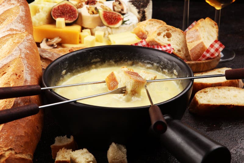 Gourmet Swiss fondue dinner on a winter evening with assorted cheeses on a board alongside a heated pot of cheese fondue with two