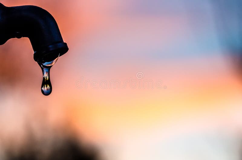 Goutte de l'eau sortant d'un robinet en métal avec un fond mou photographie stock Goutte de l'eau sortant d'un robinet en métal avec un fond mou photographie stock