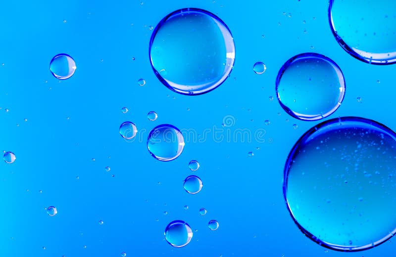 Blue oil drops in water. Bubbles of different sizes on blue abstract background. Blue oil drops in water. Bubbles of different sizes on blue abstract background