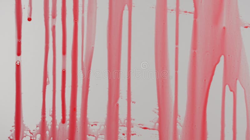 Gouttes de peinture rouge sur la surface de verre. Une image de closeup de peinture rouge qui dérive une surface de verre créant un motif abstrait. le contraste saisissant entre la peinture rouge et le verre transparent ajoute un effet spectaculaire.