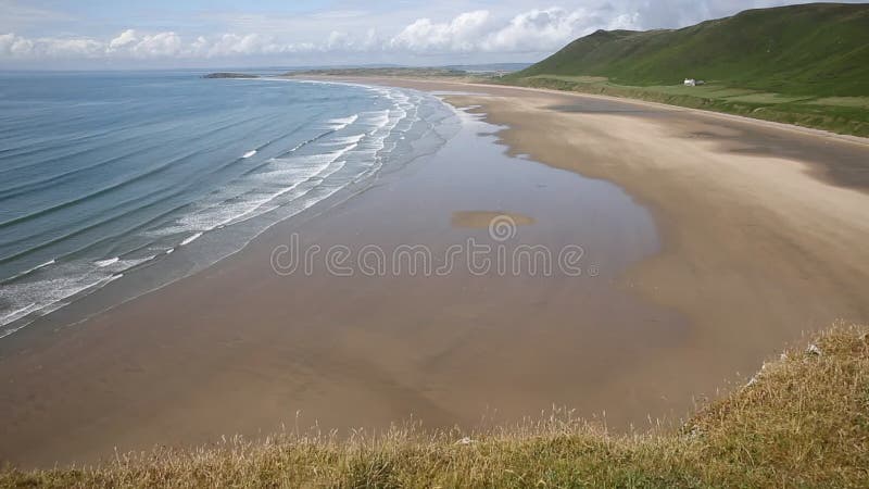 The Gower Wales Rhossili beach with waves breaking on the sand