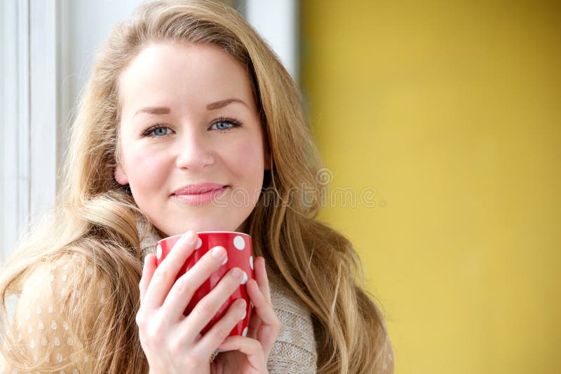 Close up portrait of a beautiful young woman enjoying a cup of coffee at home. Close up portrait of a beautiful young woman enjoying a cup of coffee at home