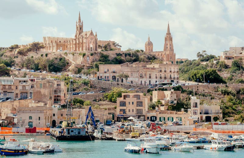 Gozo island port view with fishing boats and old churches on a hill