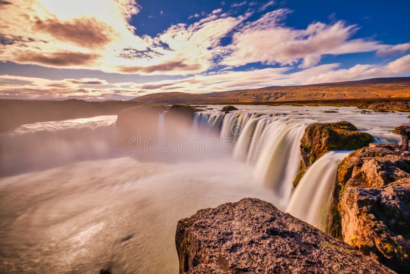 Goðafoss en exposición larga, cielo azul y blanco, colores cálidos de otoño en los rayos del sol imagenes de archivo Goðafoss en exposición larga, cielo azul y blanco, colores cálidos de otoño en los rayos del sol imagenes de archivo
