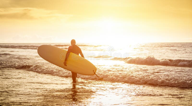 Grabbsurfaren som går med surfingbrädan på solnedgången i Tenerife - surfa begreppet
