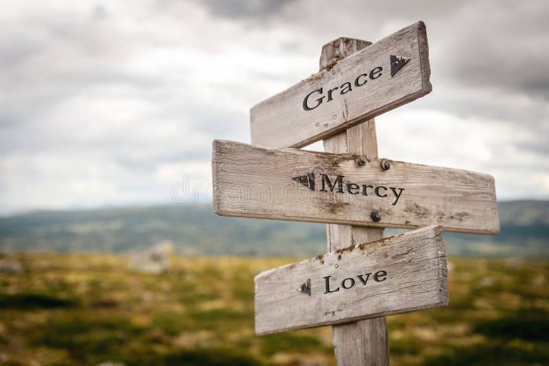 grace mercy love text engraved on old wooden signpost outdoors in nature